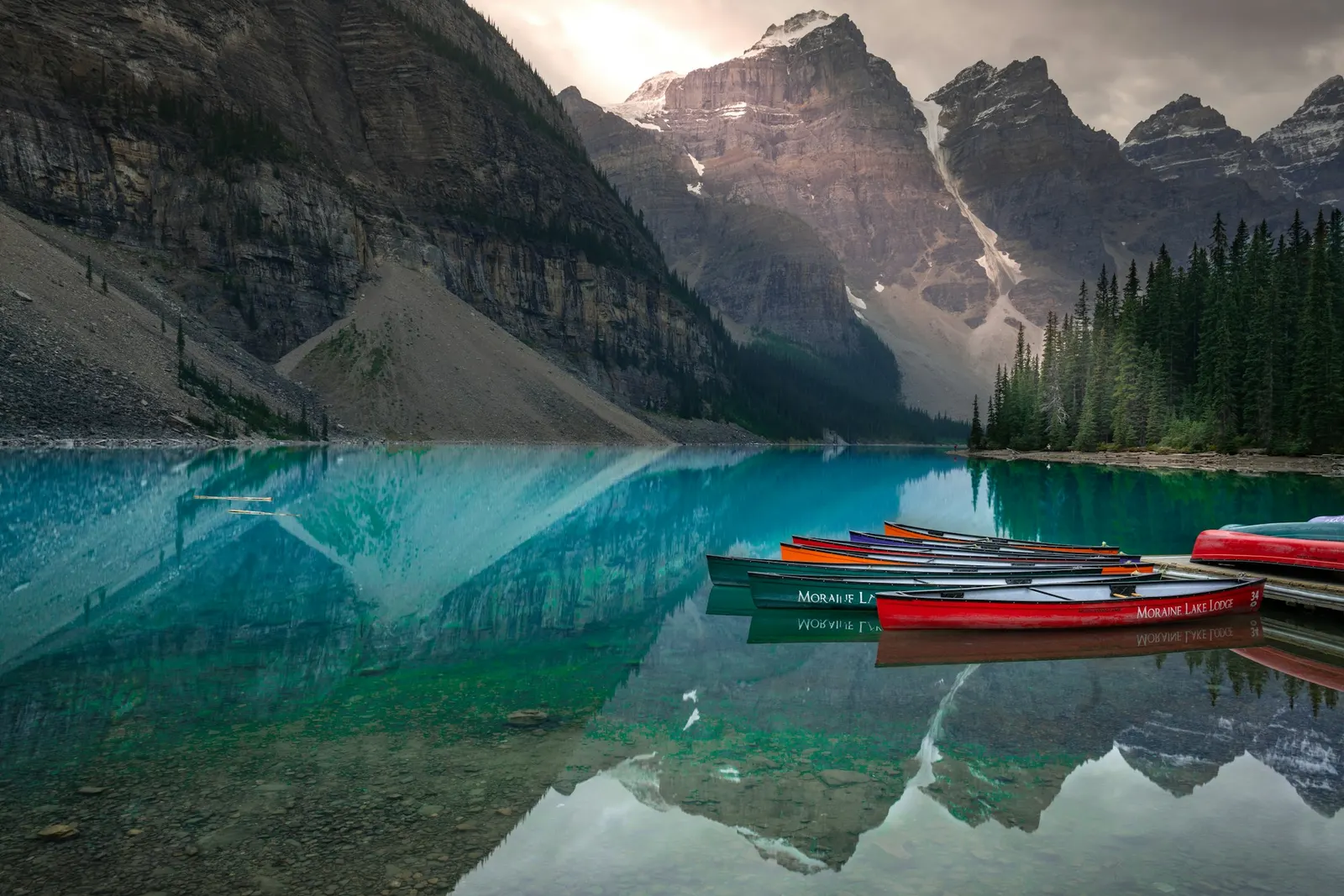 Row of colourful rental canoes at a dock on a turquoise mountain lake